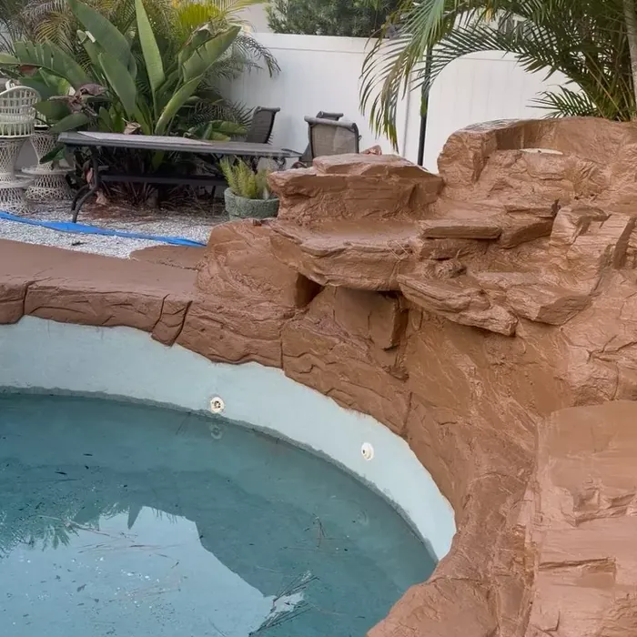 Finished pool deck coating surrounding a rock waterfall