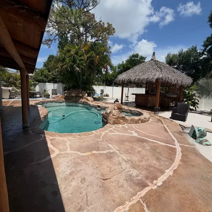 Finished pool deck coating beside a backyard tiki hut